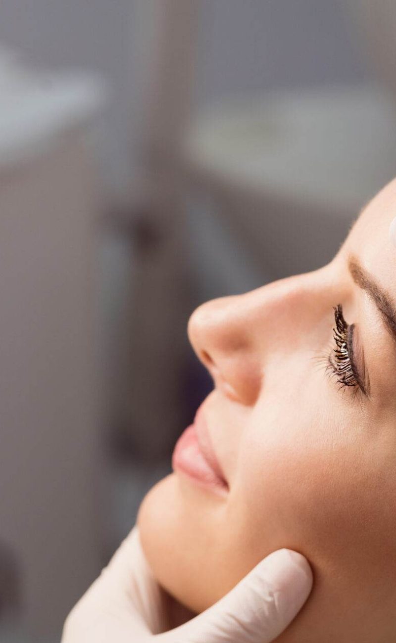 Hands of doctor examining womans face for cosmetic treatment at clinic
